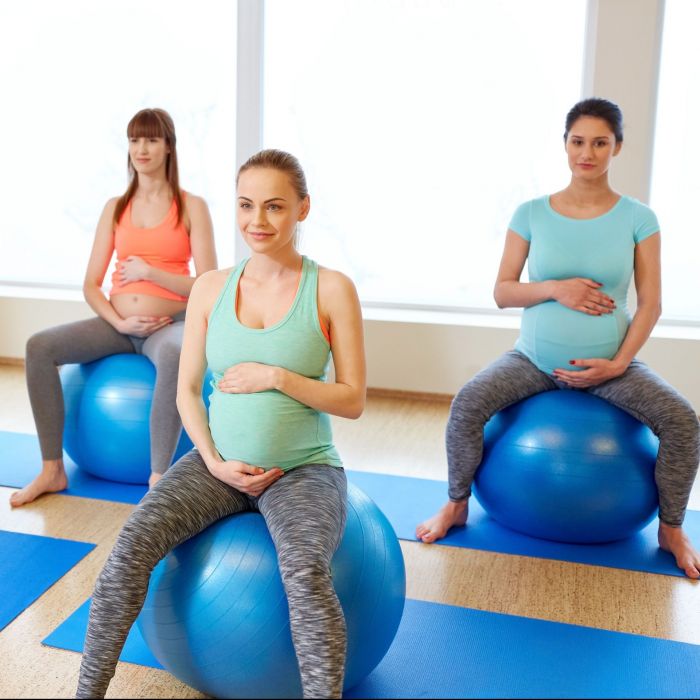 pregnancy, sport, fitness, people and healthy lifestyle concept - group of happy pregnant women sitting on exercise balls in gym