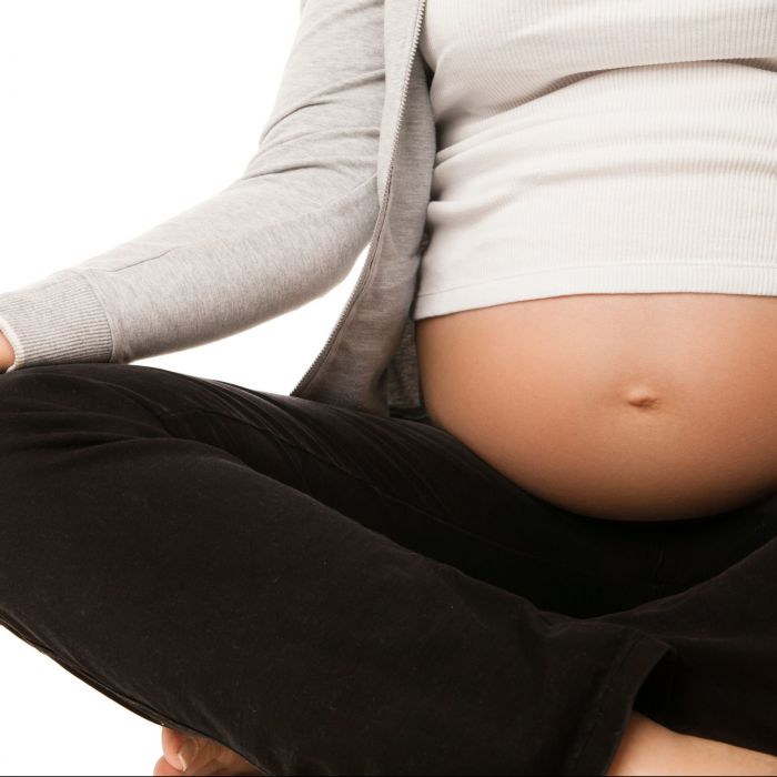 Pregnant woman relax doing yoga, sitting in lotus position over white background